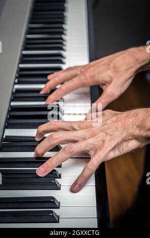 Extrem dünner Pianist, der die Tasten eines Klaviers spielt Stockfoto