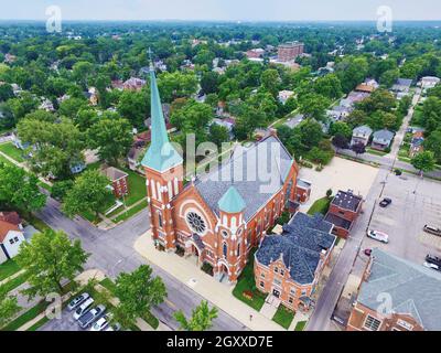 Antenne einer großen Kirche mit einer verrosteten Kupferspirale am Himmel, umgeben von kleinen Gebäuden und Bäumen Stockfoto
