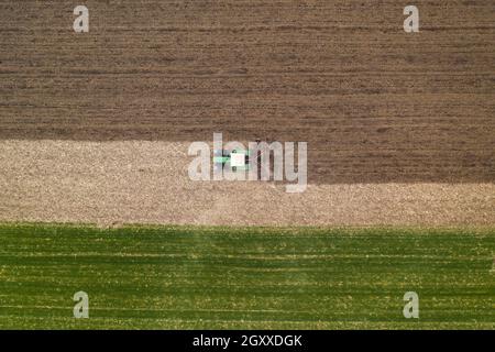 Luftaufnahme der landwirtschaftlichen Traktor Bodenbearbeitung und erschütternde gepflügten Feld, direkt über Drohne pov Bild von Maschinen arbeiten auf Ackerland Stockfoto