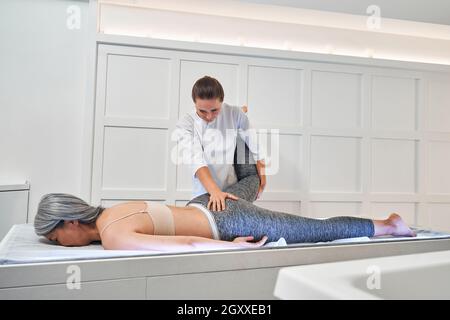 Nahaufnahme eines Physiotherapeuten, der dem Patienten am Bein eine Therapiebehandlung gibt Stockfoto