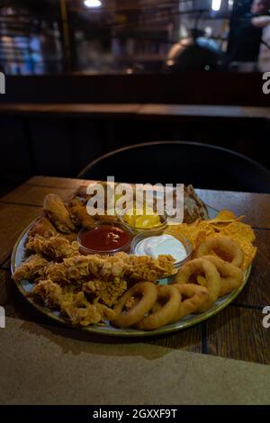 junkfood zusammen Teller mit Zwiebelringen Chicken Wings Dips . Stockfoto