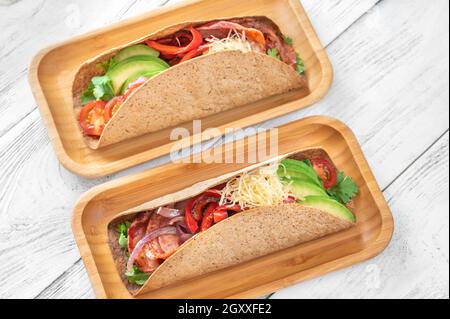 Tacos mit Schinken und Gemüse auf dem servierten Holzteller Stockfoto