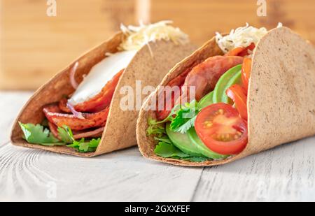 Tacos mit Schinken und Gemüse auf dem servierten Holzteller Stockfoto