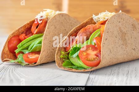 Tacos mit Schinken und Gemüse auf dem servierten Holzteller Stockfoto