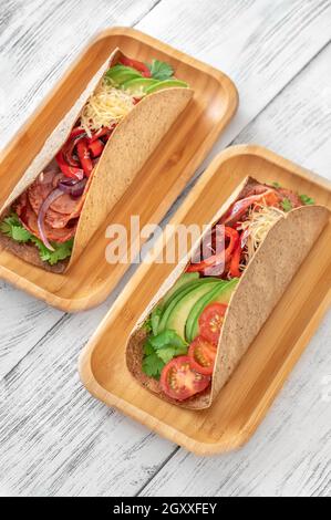 Tacos mit Schinken und Gemüse auf dem servierten Holzteller Stockfoto