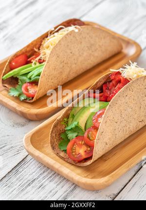 Tacos mit Schinken und Gemüse auf dem servierten Holzteller Stockfoto