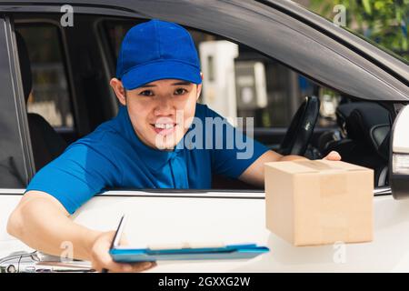 Asiatische junge Lieferung Mann Kurier tragen Uniform im Auto Dokumente in der Zwischenablage halten Übergabe an den Kunden an Signatursignatur Für den Eingang der Lieferung p Stockfoto