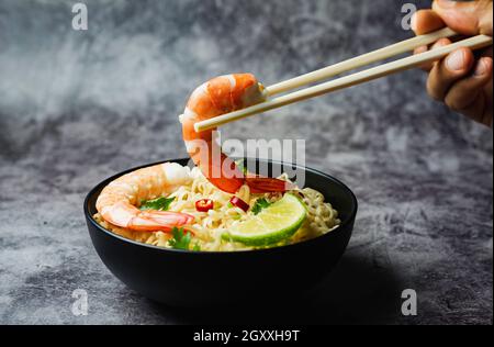 Hand mit Essstäbchen Abholung Instant Nudeln auf Beton Hintergrund. Stockfoto