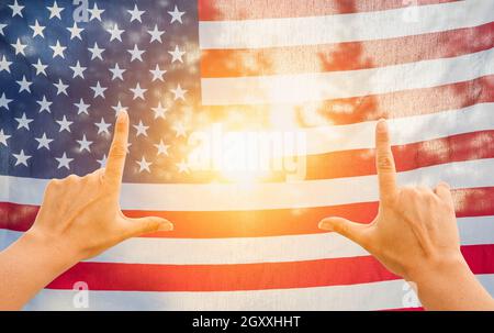 Hände Framing Sonne durch amerikanische Flagge Stockfoto