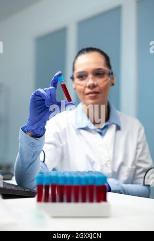 Wissenschaftlerin Ärztin bei der Analyse von transparentem Vakuumier mit Blut beim mikrobiologischen Experiment im Krankenhauslabor. Biologe Forscher entwickeln medizinischen Impfstoff gegen Viruserkrankungen Stockfoto