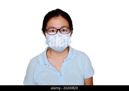 Asiatische Frau mittleren Alters in blauem T-Shirt trägt medizinische Maske, isoliert auf weißem Hintergrund. Coronavirus- oder Covid-19-Schutzkonzept. Stockfoto
