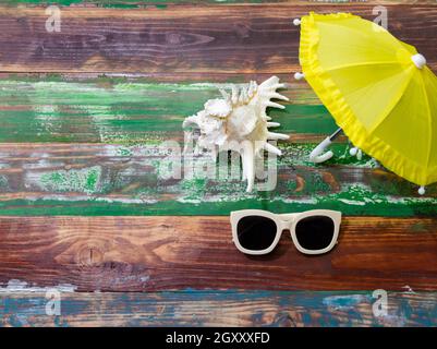 Sommer Hintergrund mit Strand-Accessoires von weißen Sonnenbrillen und gelben Regenschirm auf verwitterten Holzhintergrund Stockfoto