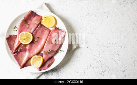 Frische Tintenfische oder Tintenfische für gekochte Speisen. Frischer roher Tintenfisch. Roher Tintenfisch mit Zitrone. Draufsicht und Kopierbereich für Ihren Text Stockfoto