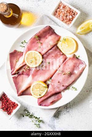 Frische Tintenfische oder Tintenfische für gekochte Speisen. Frischer roher Tintenfisch. Roher Tintenfisch mit Zitrone. Draufsicht und Kopierbereich für Ihren Text Stockfoto