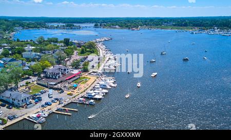Docks entlang der Seenküste voller Boote und Schiffe, die im Wasser segeln Stockfoto