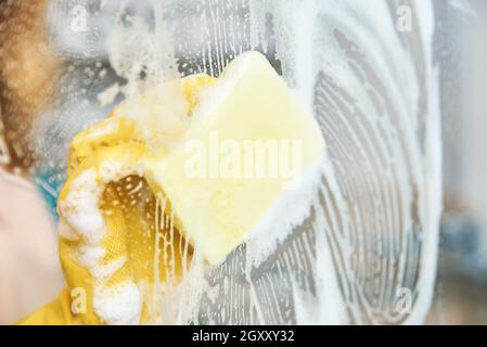 Frau in gelben Gummihandschuhen reinigt Glas Badezimmer Dusche Kabine. Hausreinigung Stockfoto