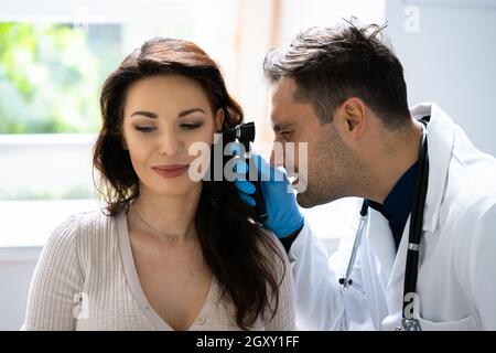 Nahaufnahme eines Arztes, der das Ohr eines Patienten mit Otoskop bemustzt Stockfoto