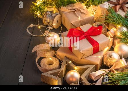 Weihnachtskomposition mit Geschenken, Kiefernästen und Weihnachtsdekorationen im Licht von Girlande-Lichtern. Seitenansicht, Kopierbereich. Stockfoto