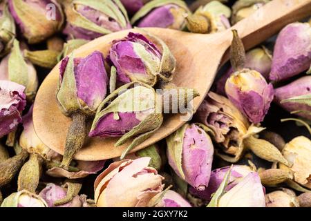 Holzlöffel mit alten getrockneten Rosenknospen aus nächster Nähe auf Haufen Von getrockneten Blumen Stockfoto