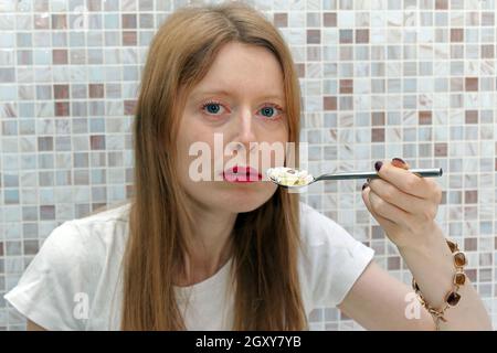 Junge Frau süchtig nach verschreibungspflichtigen Medikamenten hält Löffel voll Pillen neben einem Mund Stockfoto