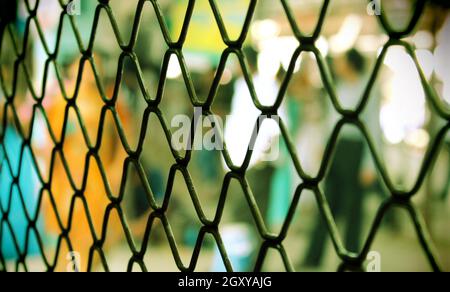 Nahtloser Metallgitter-Zaun mit bunten Unschärfe-Hintergrund und Fokus auf Zaun. Stockfoto