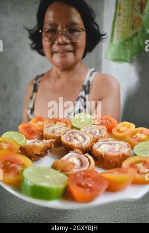 Asiatische Frau, die einen Teller mit Essen anbietet Stockfoto