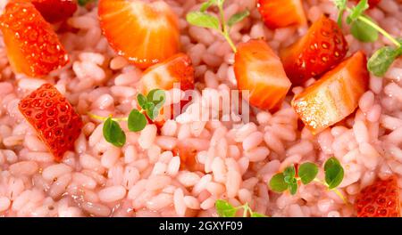 Risotto mit Erdbeerfrüchten in einem Gericht serviert. Nahaufnahme flach liegend mit Kopierplatz. Italienische Gourmetküche. Selektiver Fokus. Stockfoto