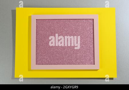 Pinkfarbener, glänzender rechteckiger Rahmen auf grau-gelbem Hintergrund mit Schatten. Vorlage Stockfoto