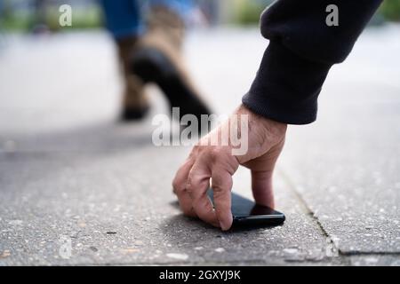 Person, die ein verlorenes Portemonnaie auf der Straße abholt Stockfoto