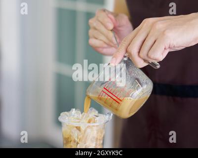 Kaffee von Hand aus einer Messbecher in eine Plastikschale gießen (Closeup ). Professioneller Barista, der Kaffee auf der Theke zubereitet. Stockfoto
