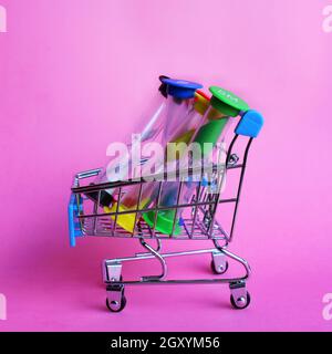 Nahaufnahme des bunten Sandglases im Einkaufswagen auf rosa Hintergrund Stockfoto