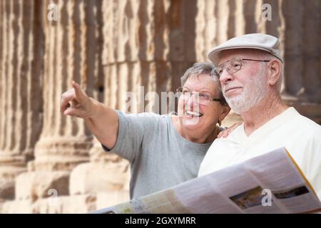 Gerne älterer Erwachsener Paar Touristen mit Broschüre Neben alten Spalte Ruinen. Stockfoto