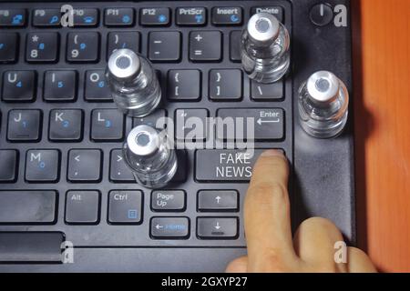 Drücken Sie die Taste mit dem Text FAKE NEWS und umgeben von einem Glasfläschchen Stockfoto