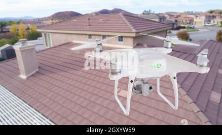 Unbemannte Luftfahrzeuge (UAV) Quadcopter Drohne in der Luft über Haus Inspektion des Daches. Stockfoto