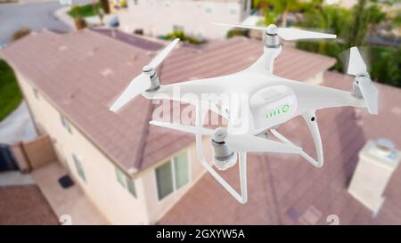 Unbemannte Luftfahrzeuge (UAV) Quadcopter Drohne in der Luft über Haus Inspektion des Daches. Stockfoto