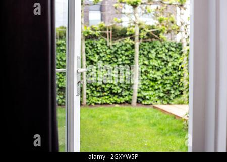 Nahaufnahme halb geöffnet moderne Tür öffnen mit verschwommenem grünen Garten Hintergrund im Sommer des modernen Haus neues Haus mit Luxus-Stil draußen Stockfoto
