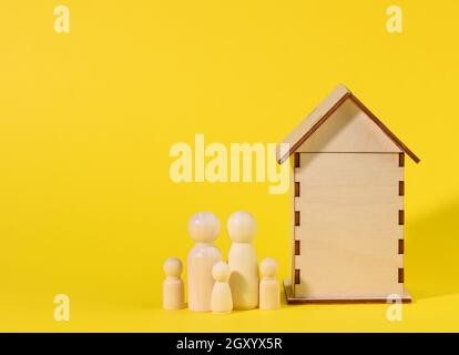 Hölzerne Familienfiguren, Modellhaus. Immobilienkauf, Mietkonzept. Umzug in neue Wohnungen, Platz kopieren Stockfoto