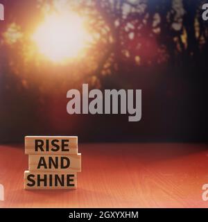 RISE AND SHINE geschrieben auf Holzfliesen mit Hintergrund von Bokeh Sonnenaufgang. Platz für Text kopieren Stockfoto
