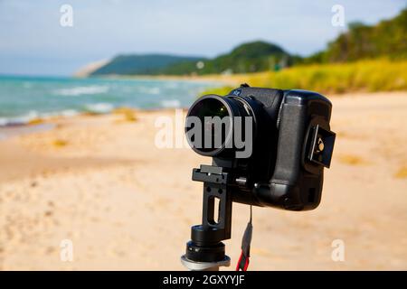 Bild einer schwarzen Kamera im Vordergrund, die auf einem Strand in Richtung Ferne zeigt Stockfoto