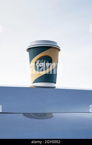 Kemerowo, Russland - 03. Oktober 2021: Shell Cafe to go Kaffeetasse steht auf der Autohaube. Pappbecher vom Shell Cafe zum Mitnehmen. Stockfoto