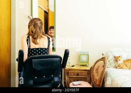 Frau in einem Rollstuhl-Roller, die sich vor einem Spiegel schminkt. Speicherplatz kopieren. Stockfoto