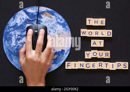 Hand-Klick-Computer-Maus auf dem Planeten Erde Globus und Holzwürfel mit Text DIE WELT AN IHREN FINGERSPITZEN. Stockfoto