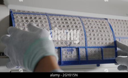 Person, die den Klimaanlagenfilter herausnimmt, Hand des Technikers, der arbeitet, indem er den staubigen Filter von der Klimaanlage zur Reinigung im Zimmer zu Hause zieht Stockfoto