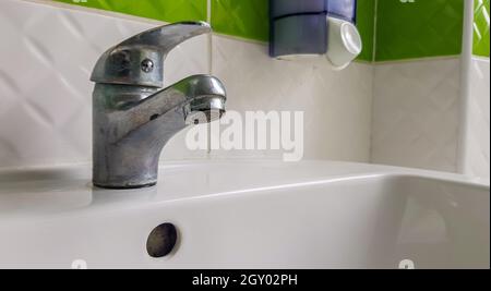 Alter Mischer für Waschbecken aus Aluminium. Wasserhahn in der Toilette für saubere Hände Stockfoto