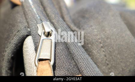 Reißverschluss schwarze Tasche Rucksack Textil-Accessoires. Nahaufnahme der Schließe. Textil, Metall und braunes Leder Stockfoto