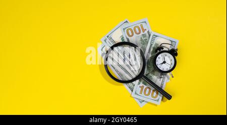 Papier american hundert Dollar Scheine und eine Lupe auf einem gelben Hintergrund. Das Konzept der Suche nach Einnahmen, Gewinn mit weniger Zeit, Belohnung. Stockfoto