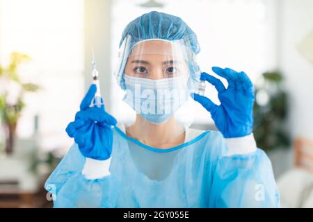 Ärzte oder Krankenschwestern tragen Kittel, Masken, Augenschilde, um eine Injektion mit einer Spritze vorzubereiten Stockfoto