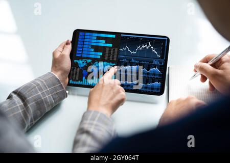 Zwei Analytiker, die KPI-Dashboard auf einem Tablet-Computer verwenden Stockfoto