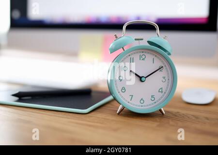 Der Wecker für zehn Uhr morgens ist auf dem Schreibtisch im Büro Stockfoto