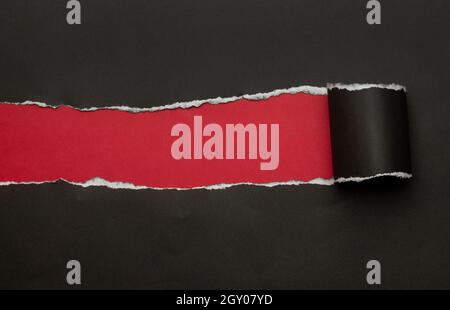 Schwarzes zerrissenes Papier auf rotem Hintergrund. Black Friday-Kampagne. Stockfoto